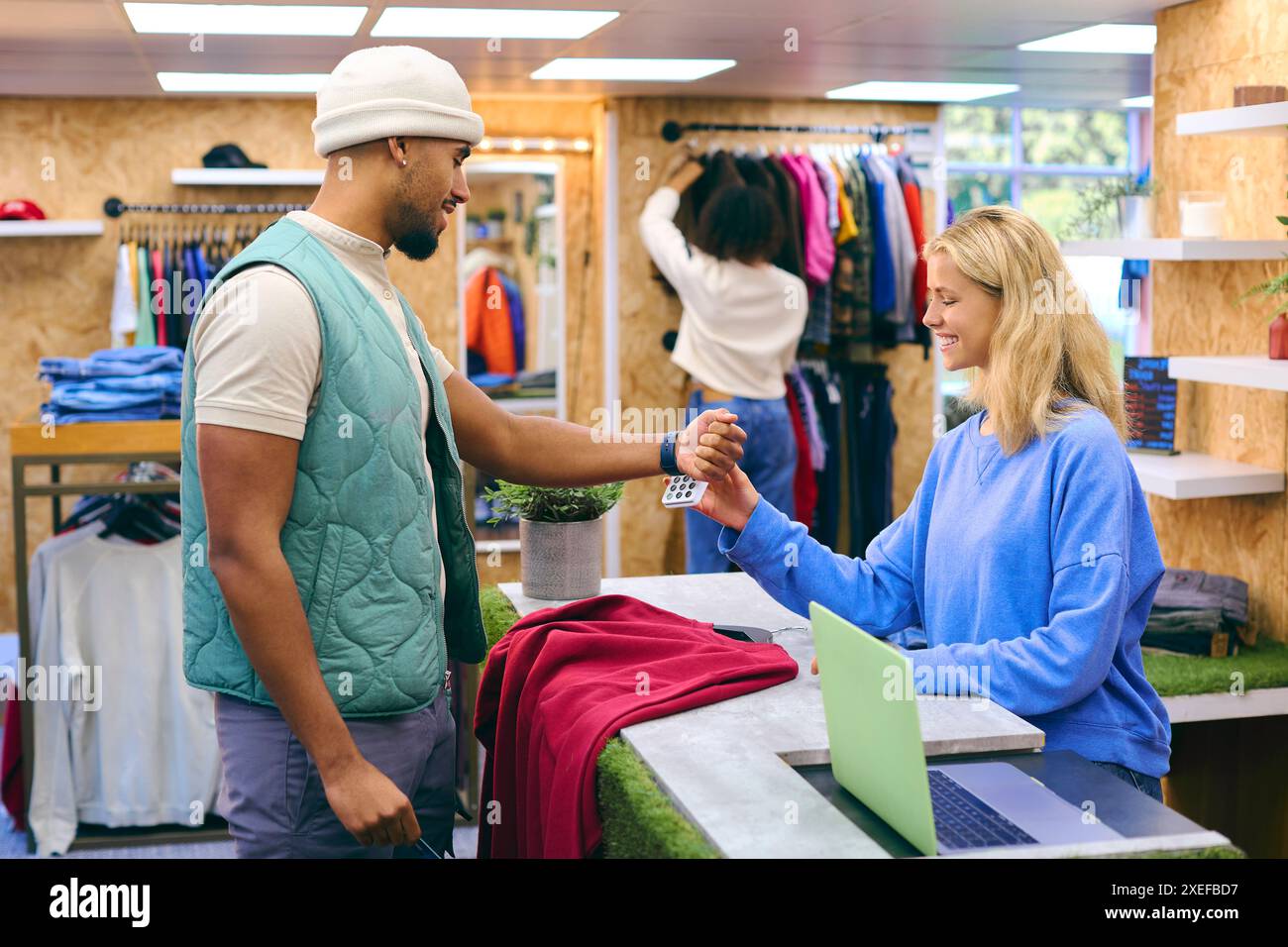 Männlicher Kunde Zahlender Vertriebsassistent Im Modegeschäft, Der Kontaktlose Zahlungen Mit Smart Watch Tätigt Stockfoto