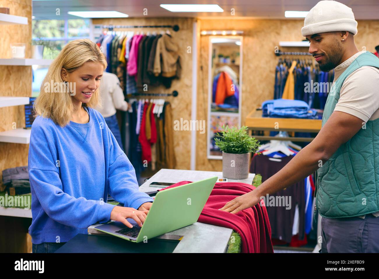 Männlicher Kunde, Der Einen Pullover Von Einem Vertriebsassistenten An Der Kasse Im Pop-Up-Mode- Oder Kleiderladen Kauft Stockfoto