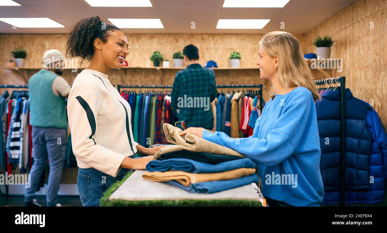 Frau, Die Kleidung Von Einer Verkäuferin Am Kassenschalter Im Fashion Store Kauft Stockfoto