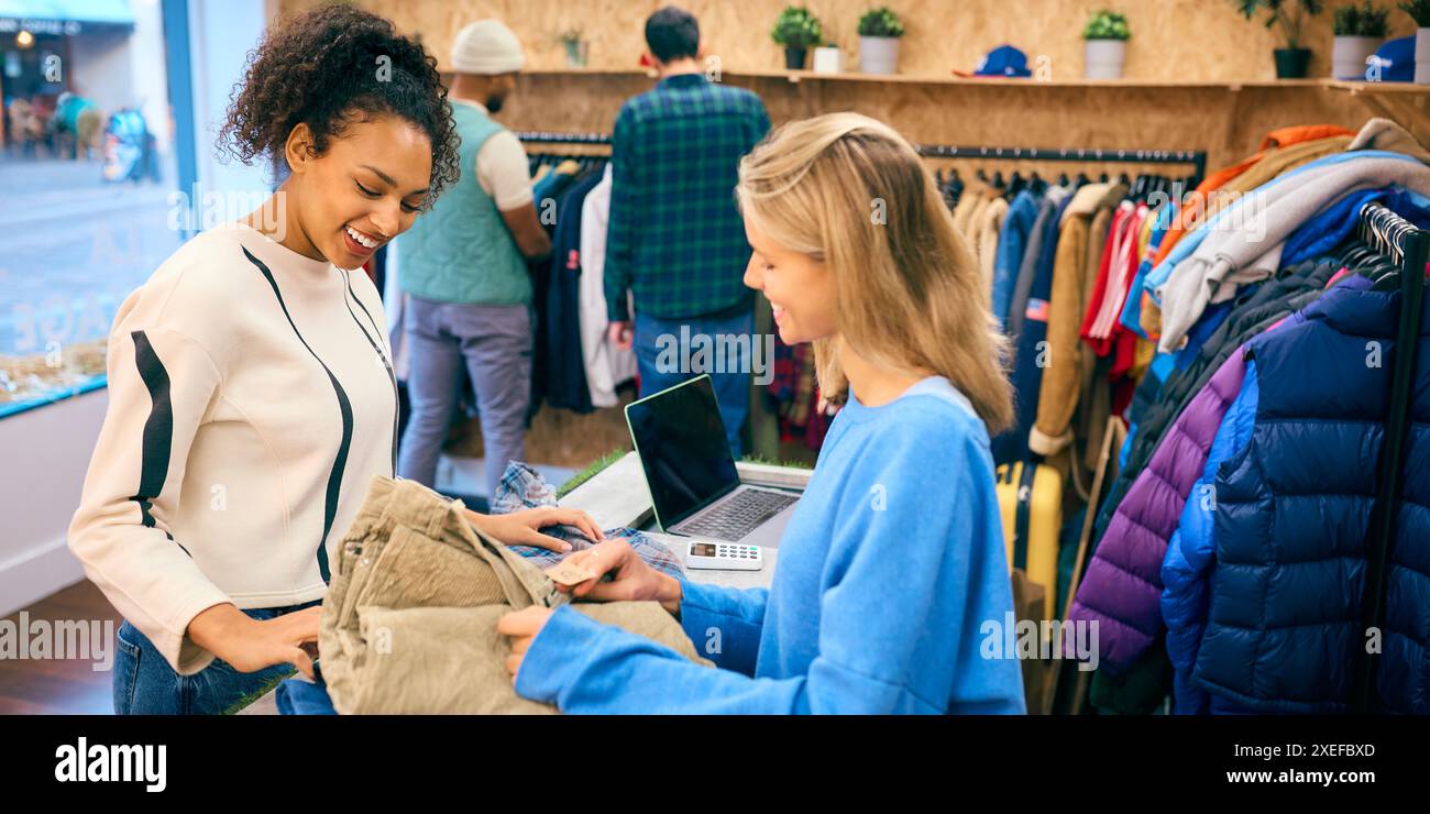 Frau, Die Ein Hemd Von Einer Verkäuferin Am Kassenschalter Im Fashion Store Kauft Stockfoto