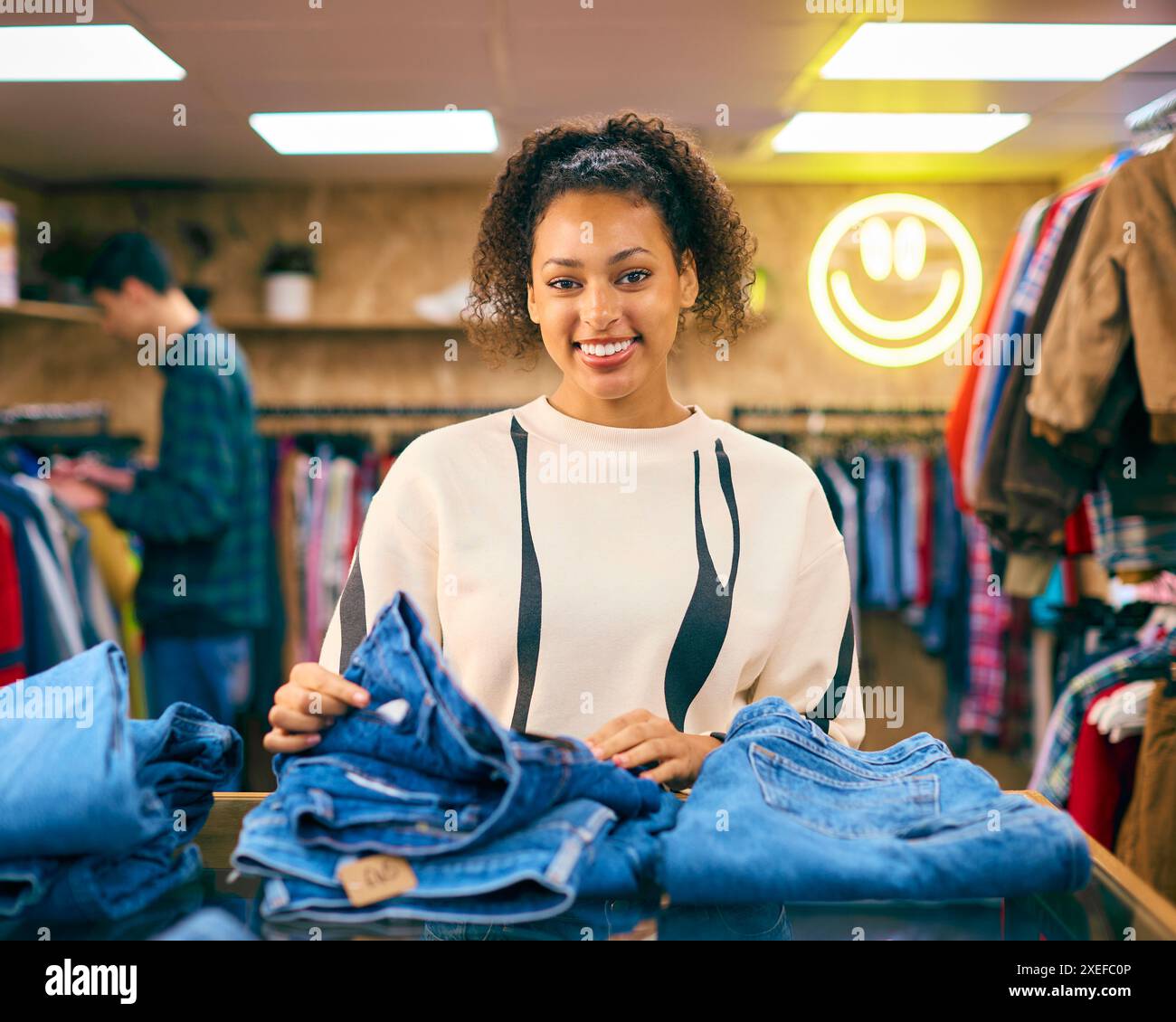 Porträt Der Verkäuferin Oder Des Kunden, Die Jeans Im Mode- Oder Bekleidungsgeschäft Sortieren Stockfoto