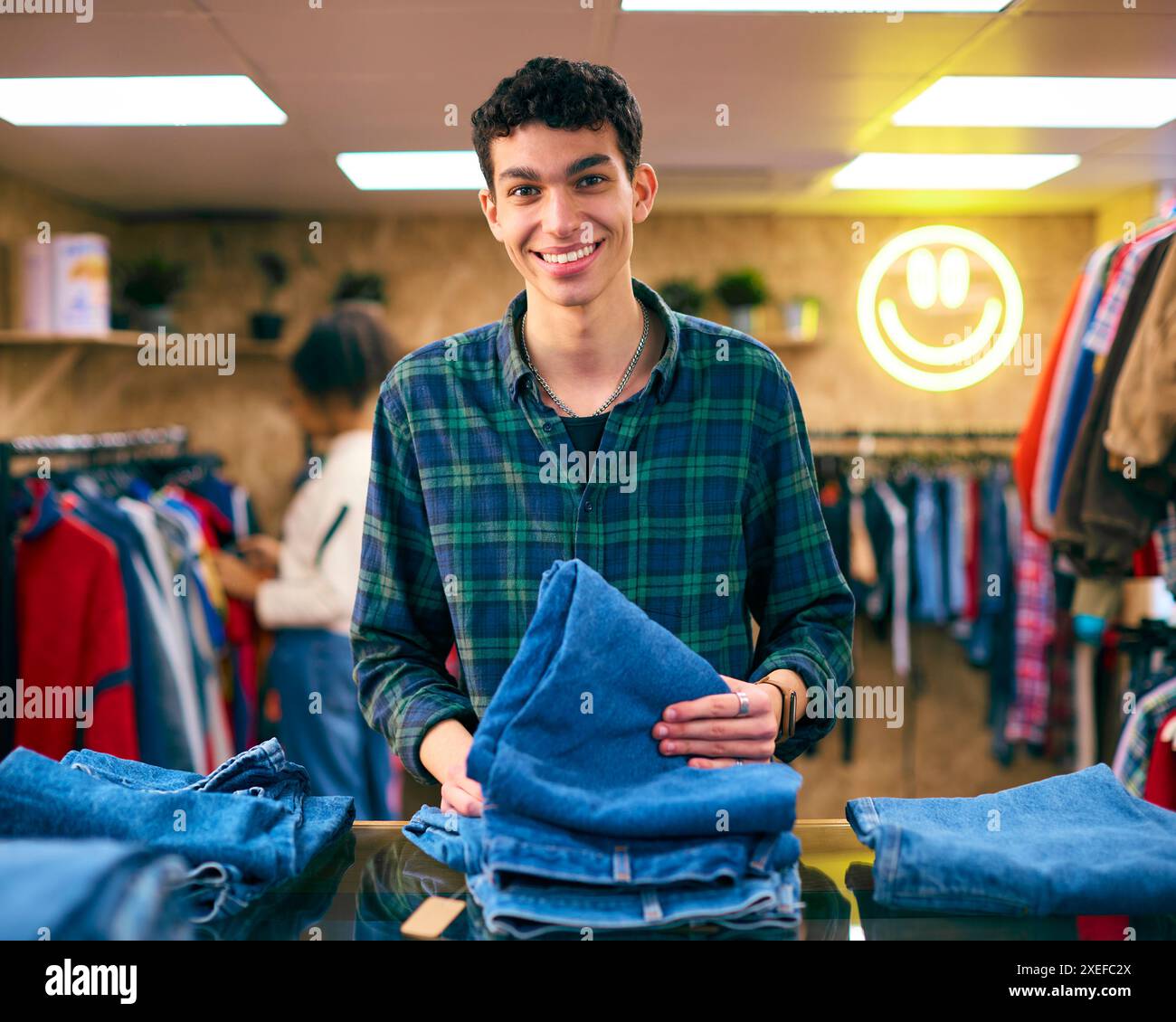 Porträt Eines Männlichen Vertriebsassistenten Oder Kunden, Der Im Fashion Store Jeans Sortiert Und Ansieht Stockfoto