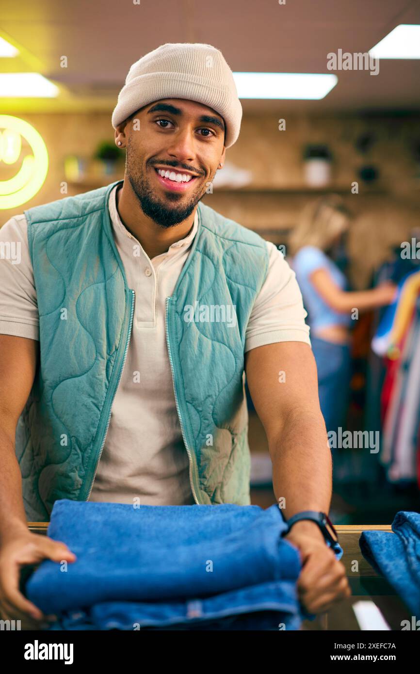 Porträt Eines Männlichen Vertriebsassistenten Oder Kunden, Der Im Fashion Store Jeans Sortiert Und Ansieht Stockfoto