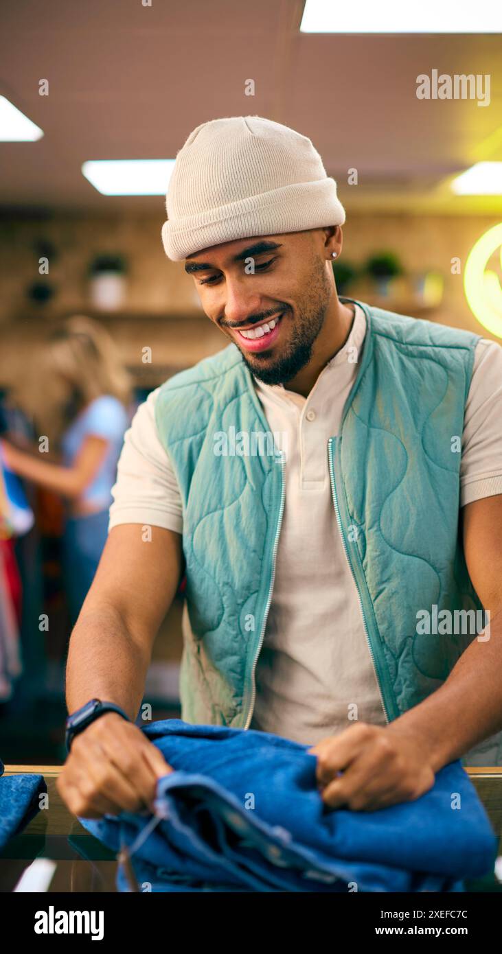 Männlicher Vertriebsmitarbeiter Oder Kunde Sortieren Und Sehen Sich Jeans Im Fashion Store An Stockfoto