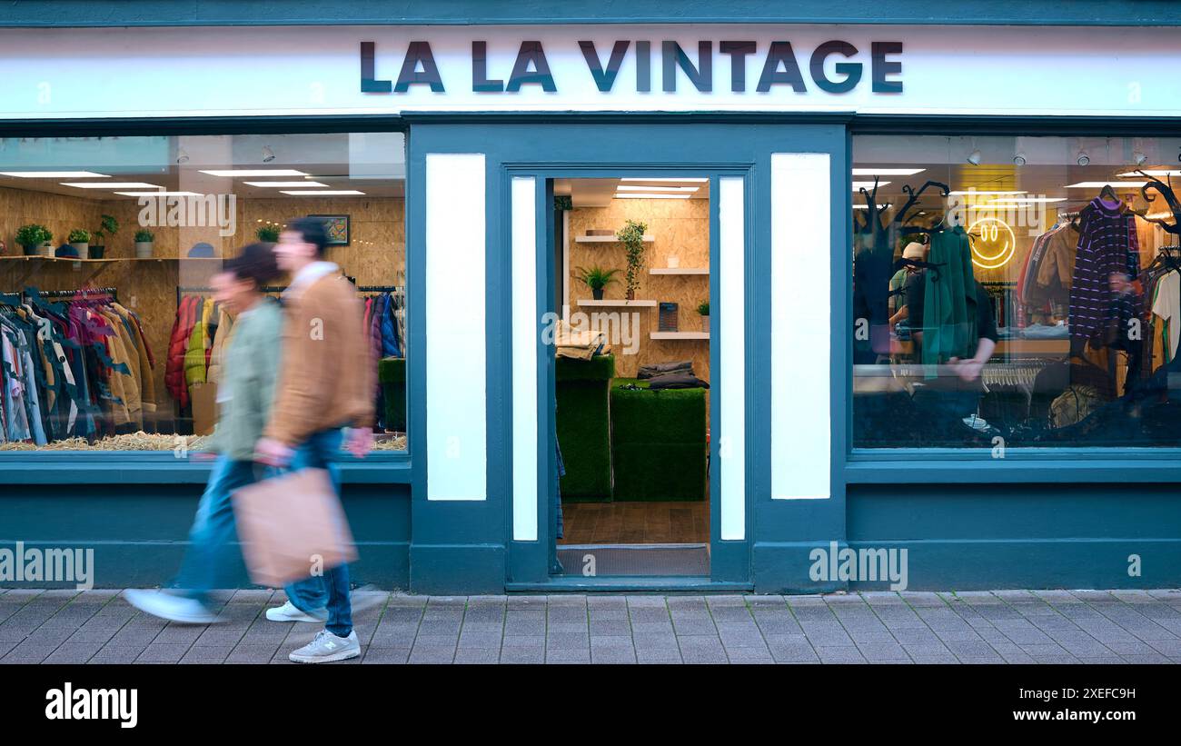 Leute Mit Einkaufstaschen, Die An Der Außenseite Von Vintage Fashion Oder Kleiderladen Mit Motion Blur Vorbeigehen Stockfoto
