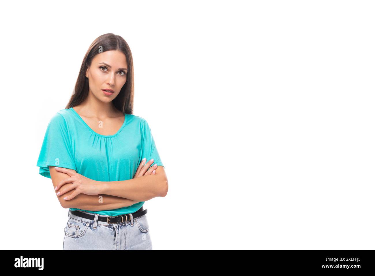 Junge gut gepflegte kaukasische Brünette Frau mit langen Haaren in einem blauen T-Shirt isoliert auf weißem Hintergrund mit Kopierraum Stockfoto