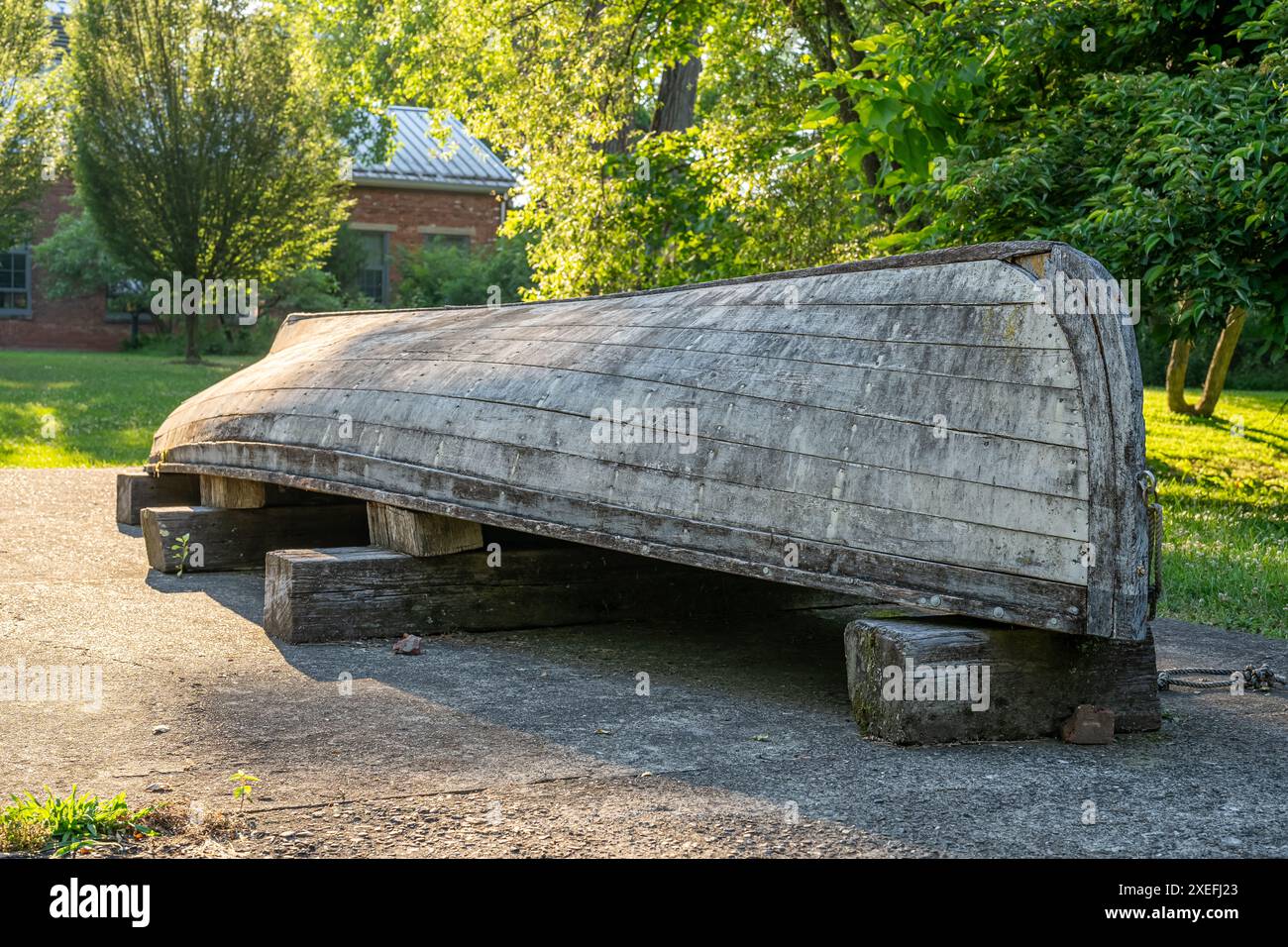 Altes, verwittertes, graues hölzernes Ruderboot auf dem Kopf, umgedreht, auf Blöcken. Stockfoto