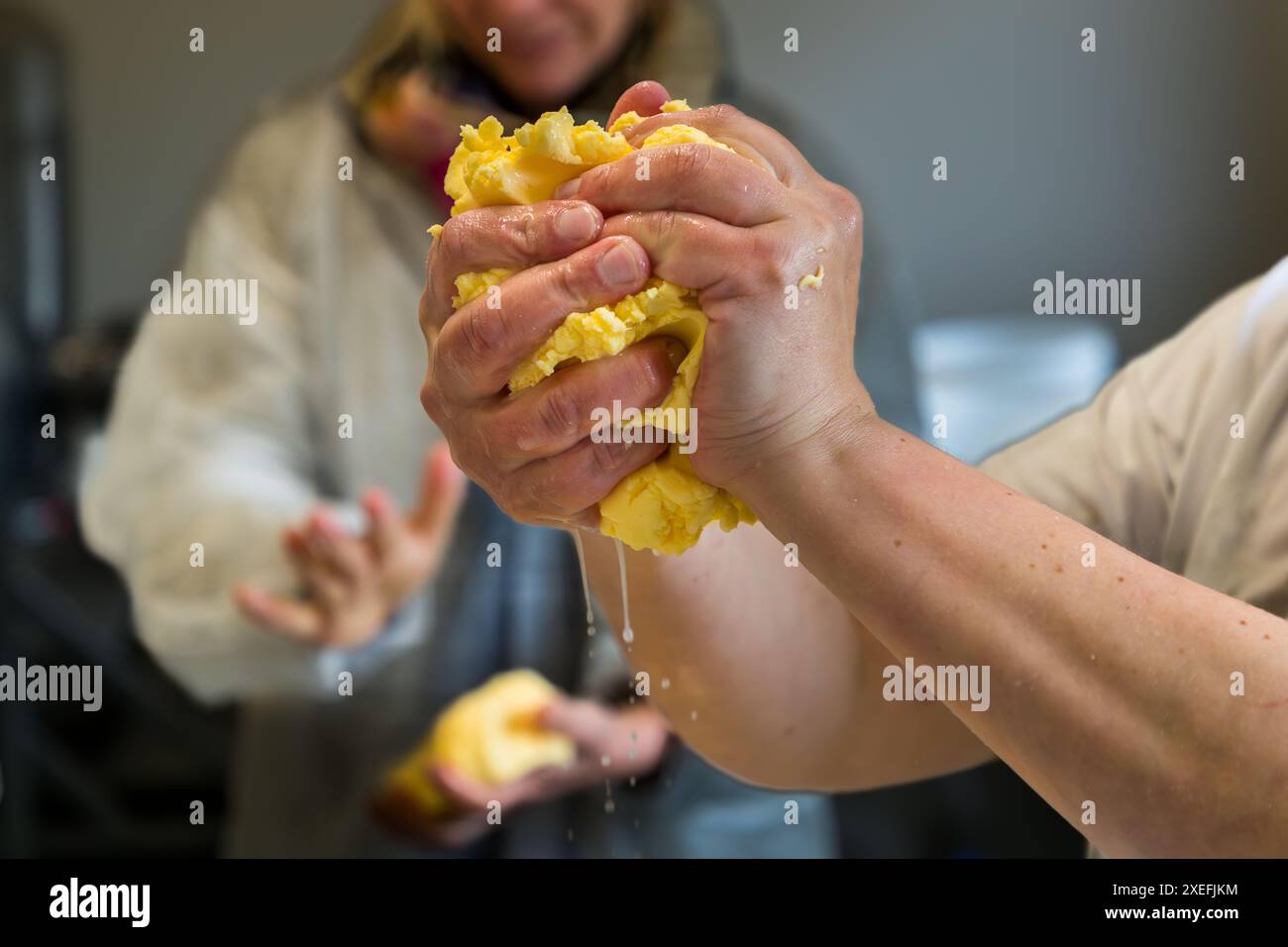 Käsemacherin und Landwirtin Bettina Hubert drückt mit ihren Händen Wasser aus der frisch aufgerührten Butter . Butterproduktion in der Käserei der Filzmoosalm. Promegg, Großarl, Salzburg, Österreich Stockfoto