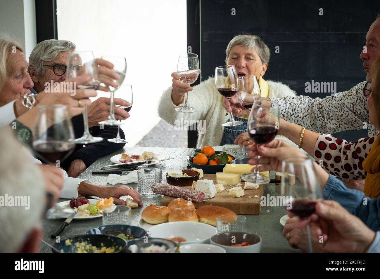 Toast auf Freundschaft: Senioren feiern mit Wein und Gourmet-Aufstrich Stockfoto