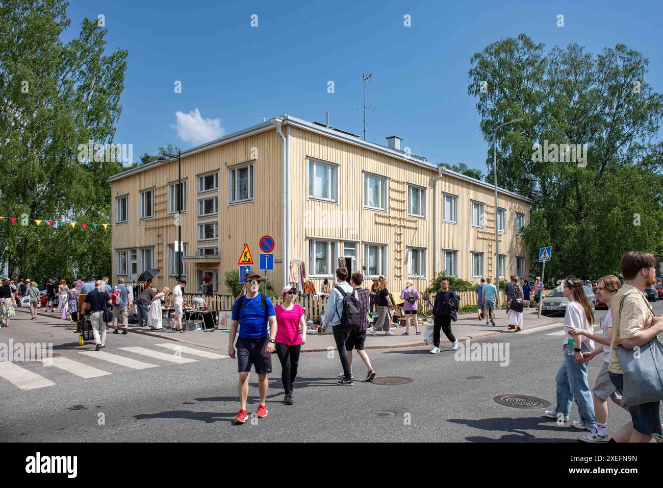 Menschen, die die Straße überqueren, können beim Kumpulan kyläjuhlat oder der Kumpula Village Party, einer Straßenmesse im Stadtteil Kumpula in Helsinki, Finnland, teilnehmen Stockfoto