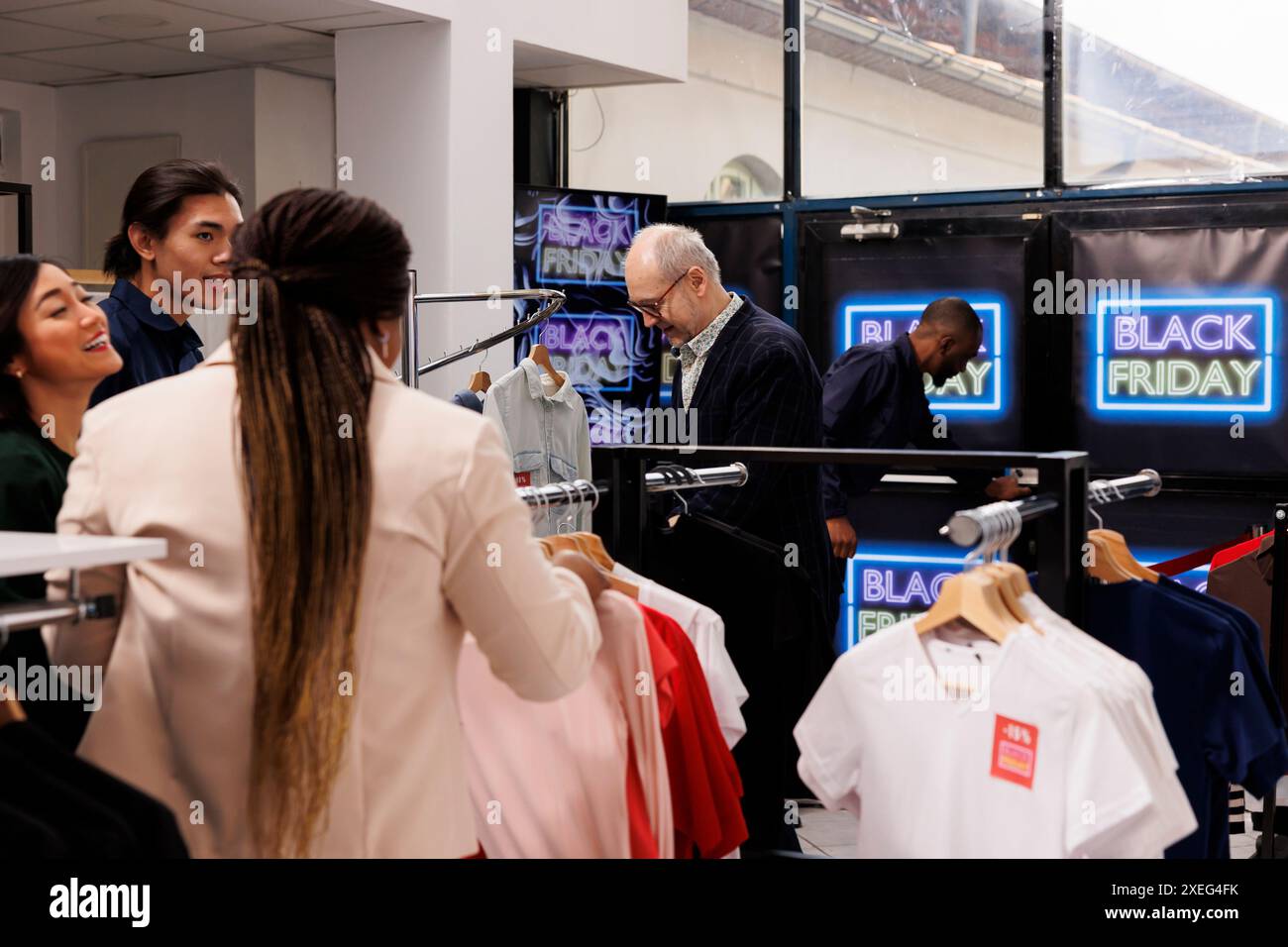 Black Friday Store Traffic. Verschiedene Kunden, die während des Verkaufs Kleidung zu ermäßigten Preisen kaufen, eine Menge von Einkäufern in einem Einkaufszentrum, auf der Jagd nach Schnäppchen während saisonaler Moderabatte Stockfoto