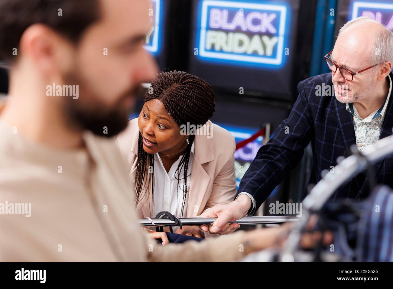 Unfreundliche, unangenehme Käufer streiten und streiten sich, während sie im Bekleidungsgeschäft nach Black Friday-Angeboten jagen, ermäßigte Modeartikel schnappen und sich gegenseitig anschreien. Die Leute streiten sich um Kleidung im Einkaufszentrum Stockfoto