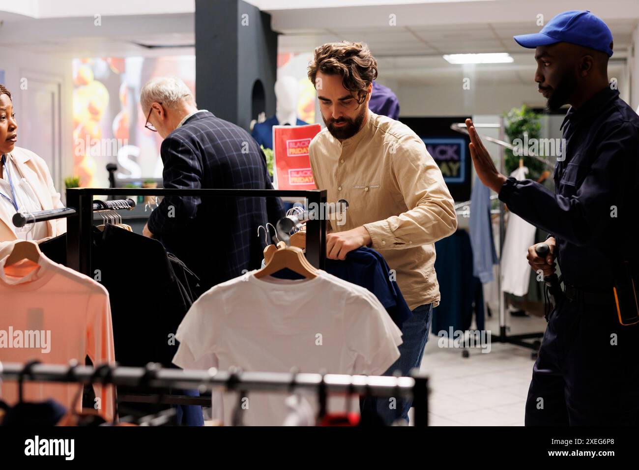 Der Sicherheitsbeamte des afroamerikanischen Mannes, der während des Black Friday-Verkaufs in einem Bekleidungsgeschäft arbeitet, bittet den aggressiven Kunden eines Shopaholic man, ruhig zu bleiben, und zeigt mit der Hand eine Stop-Geste. Sicherheit beim Einkaufen im Urlaub Stockfoto