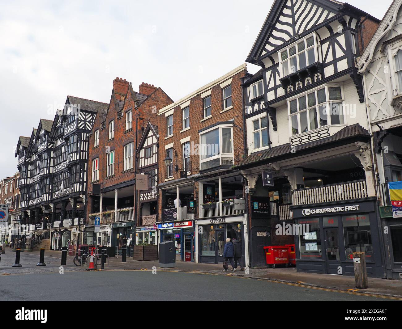 Leute, die an Geschäften und Bars in der Bridge Street Chester vorbeilaufen Stockfoto