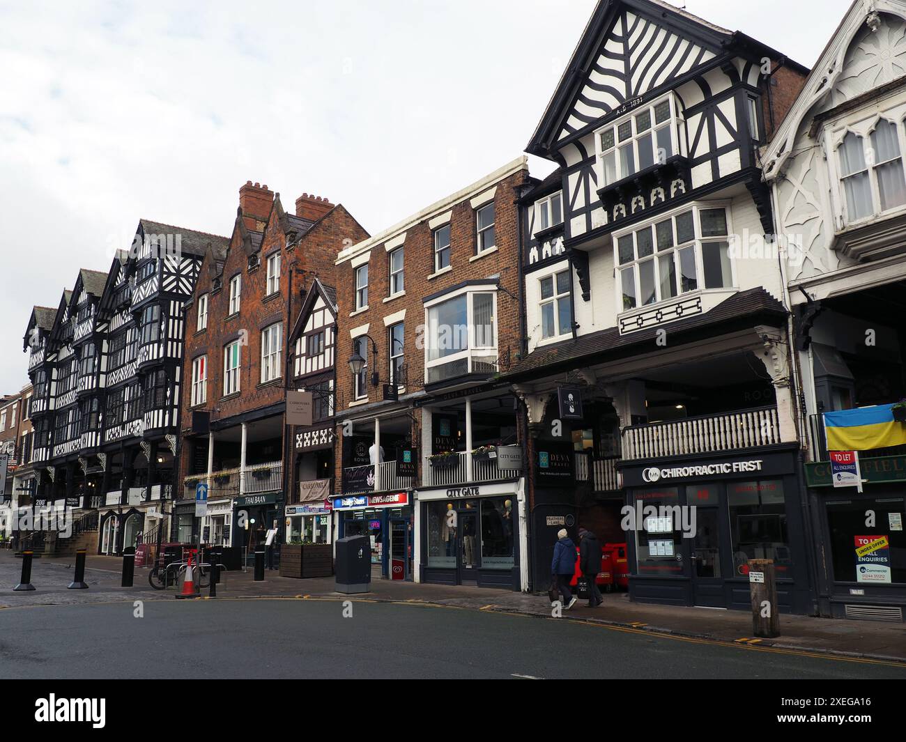 Leute, die an Geschäften und Bars in der Bridge Street Chester vorbeilaufen Stockfoto