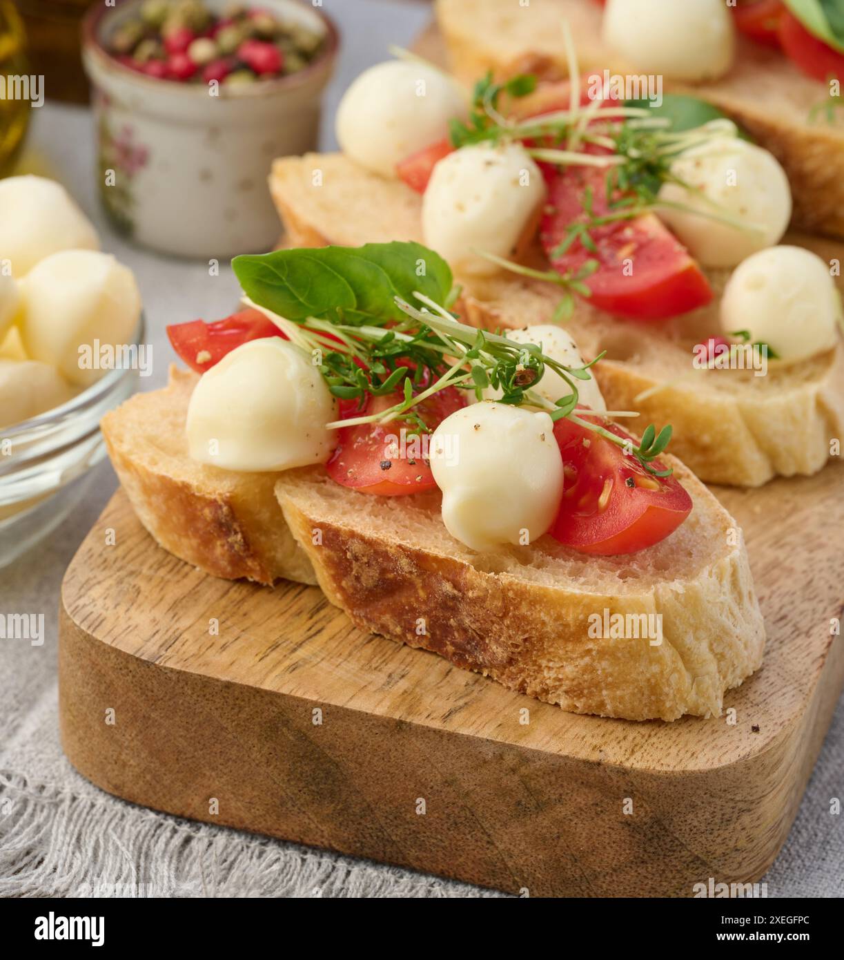 Runder Mozzarella, Kirschtomaten und Mikrogrün auf einem Stück Weißbrot, ein gesundes Sandwich Stockfoto