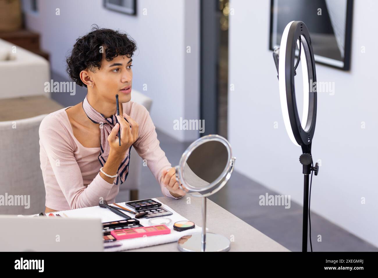 Make-up auftragen, Transgender-Frau mit Ringlicht und Spiegel am Schreibtisch zu Hause Stockfoto