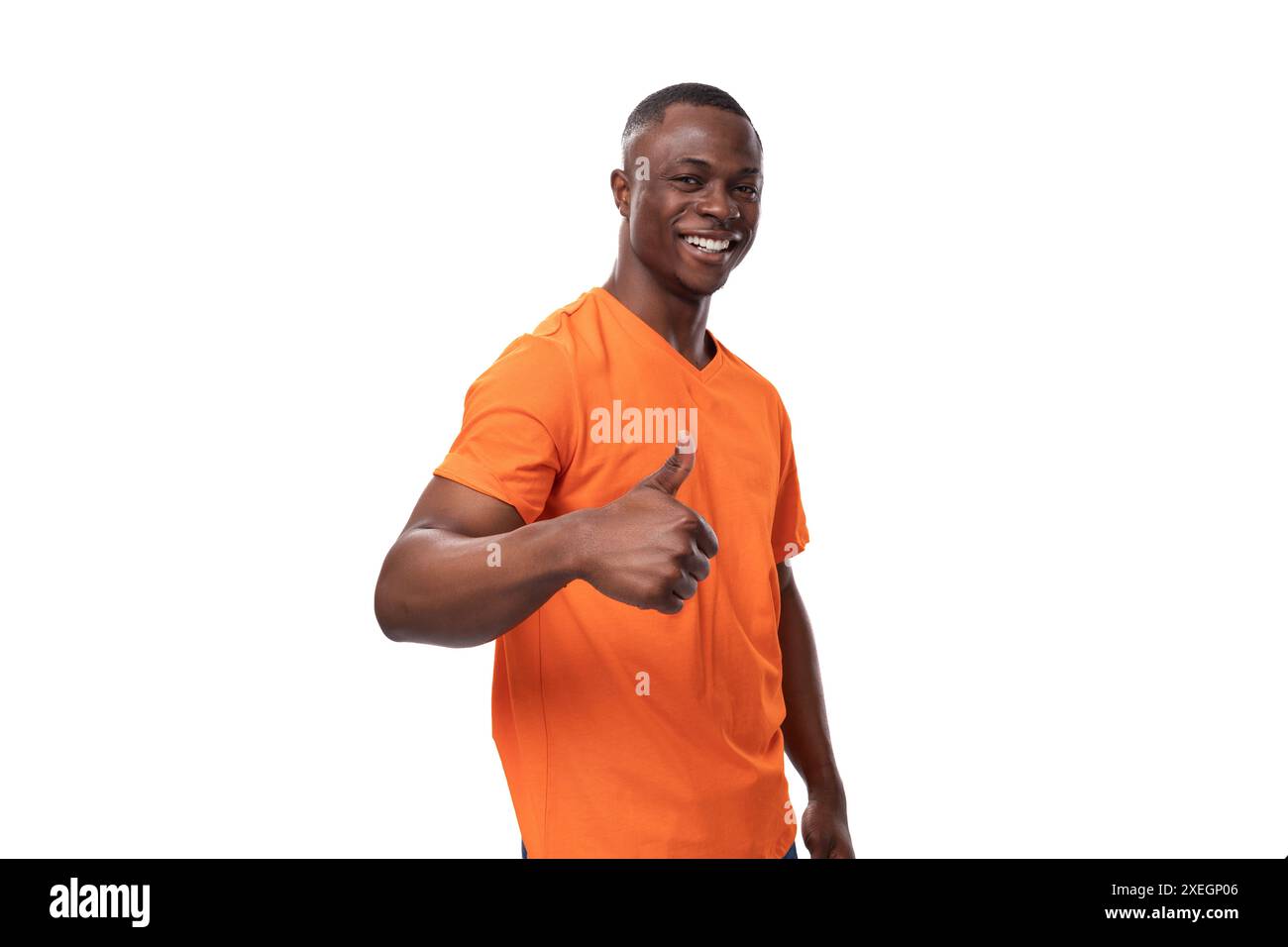 Junger positiver glücklicher amerikanischer Mann in orangefarbenem T-Shirt mit Mock-up isoliert auf weißem Hintergrund Stockfoto