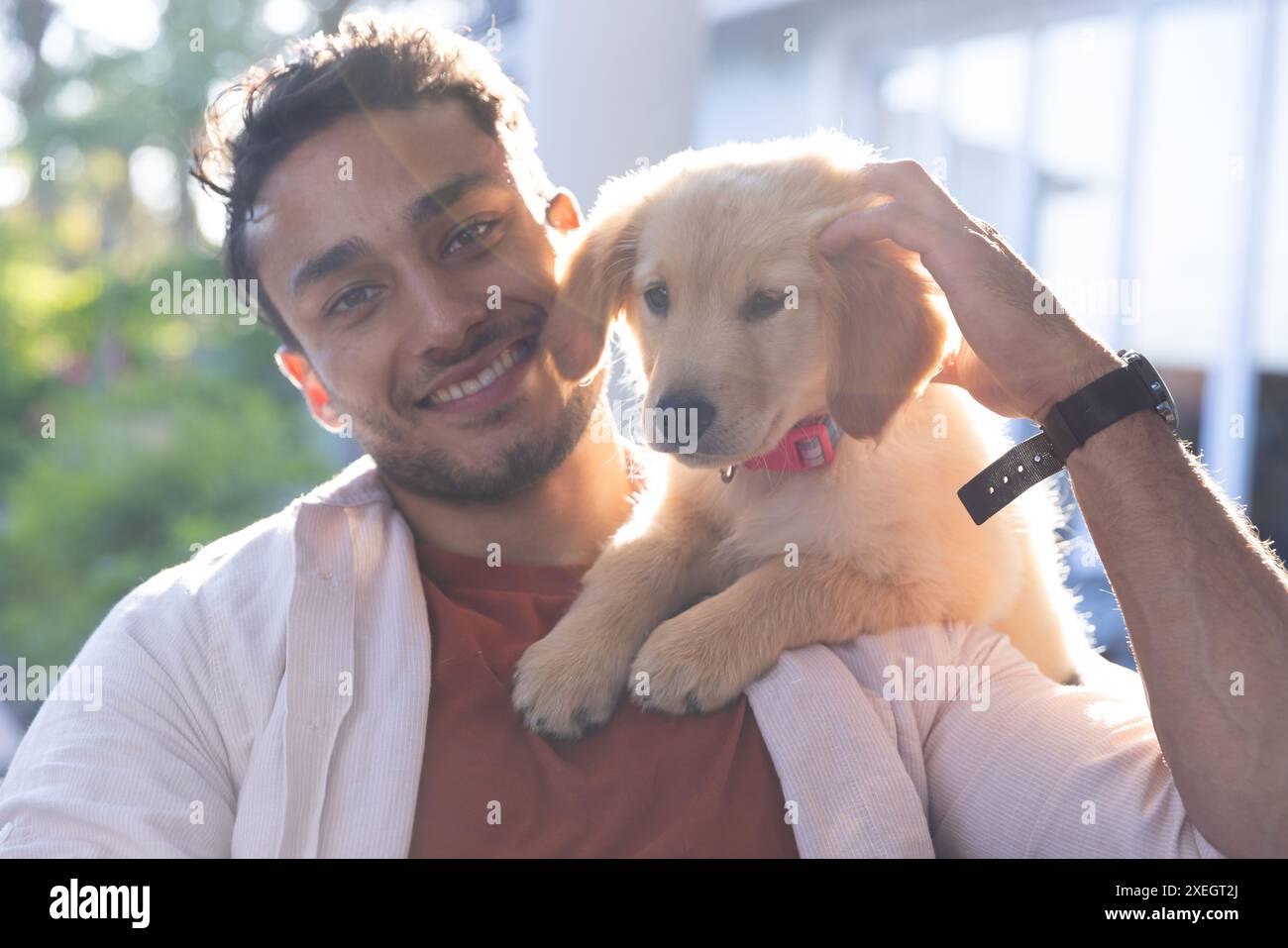 Ein lächelnder Mann hält einen niedlichen Welpen und genießt die gemeinsame Zeit zu Hause Stockfoto