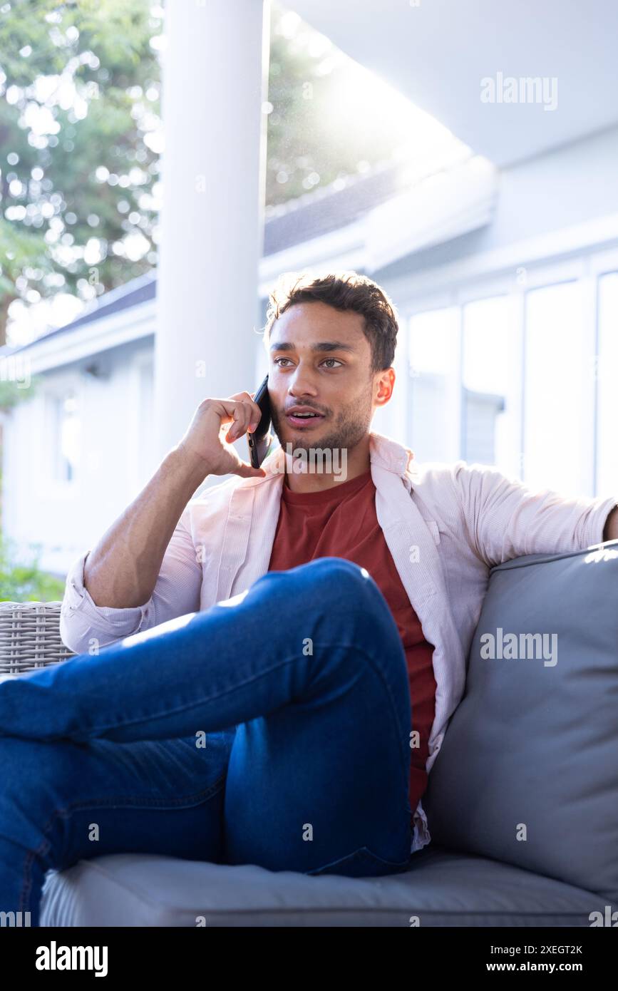 Mit dem Smartphone sprechen, Mann, der sich zu Hause auf der Couch entspannt und Gespräche genießt Stockfoto