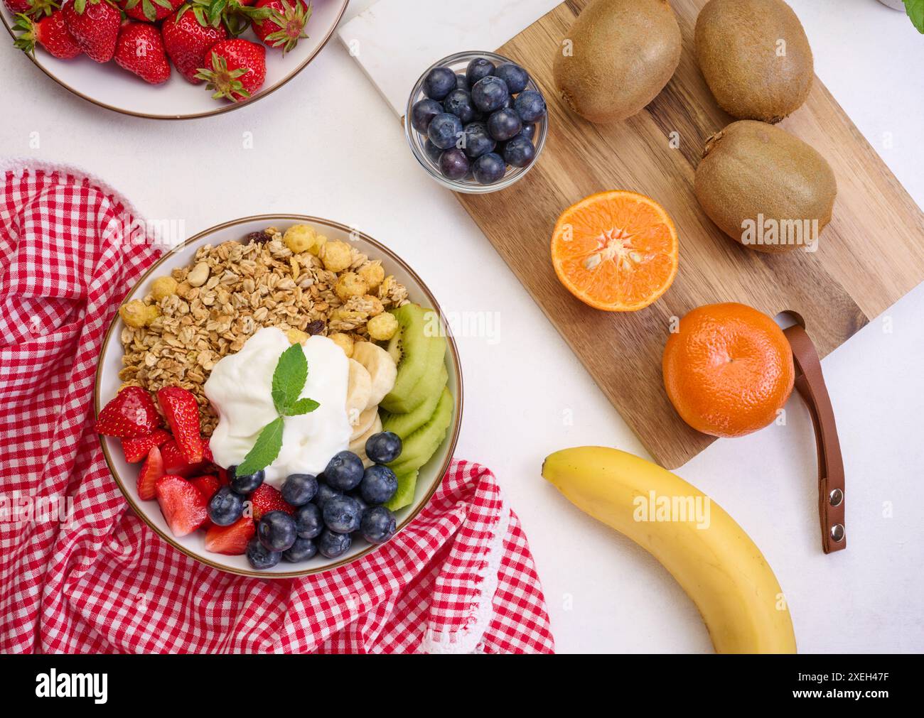 Müsli mit Erdbeeren, Kiwi, Banane und Heidelbeeren in einem runden Teller auf einem schwarzen Tisch. Gesundes und leckeres Essen Stockfoto