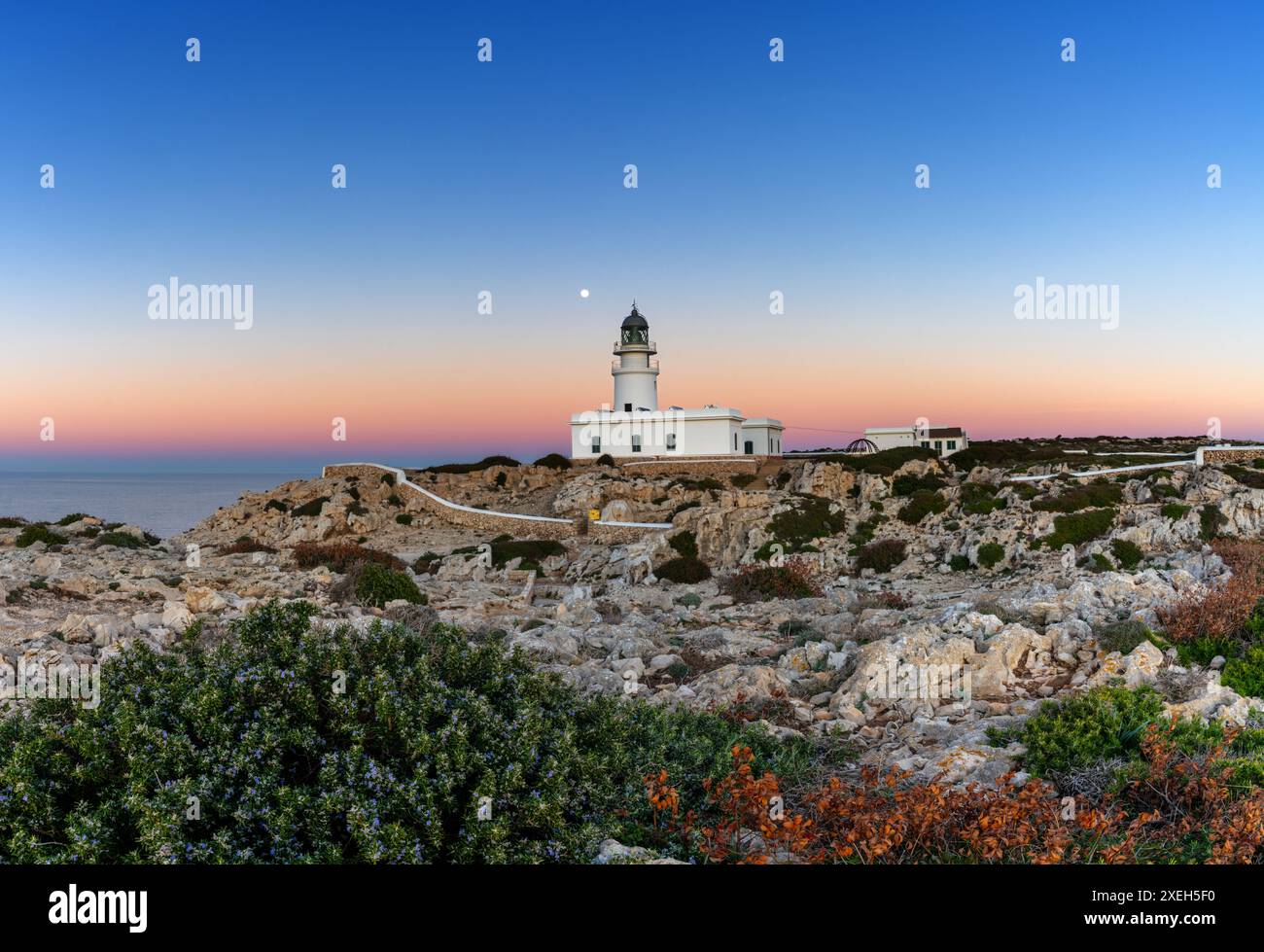 Blick auf den Leuchtturm Cap de Cavalleria auf Menorca bei Sonnenuntergang bei Vollmond Stockfoto