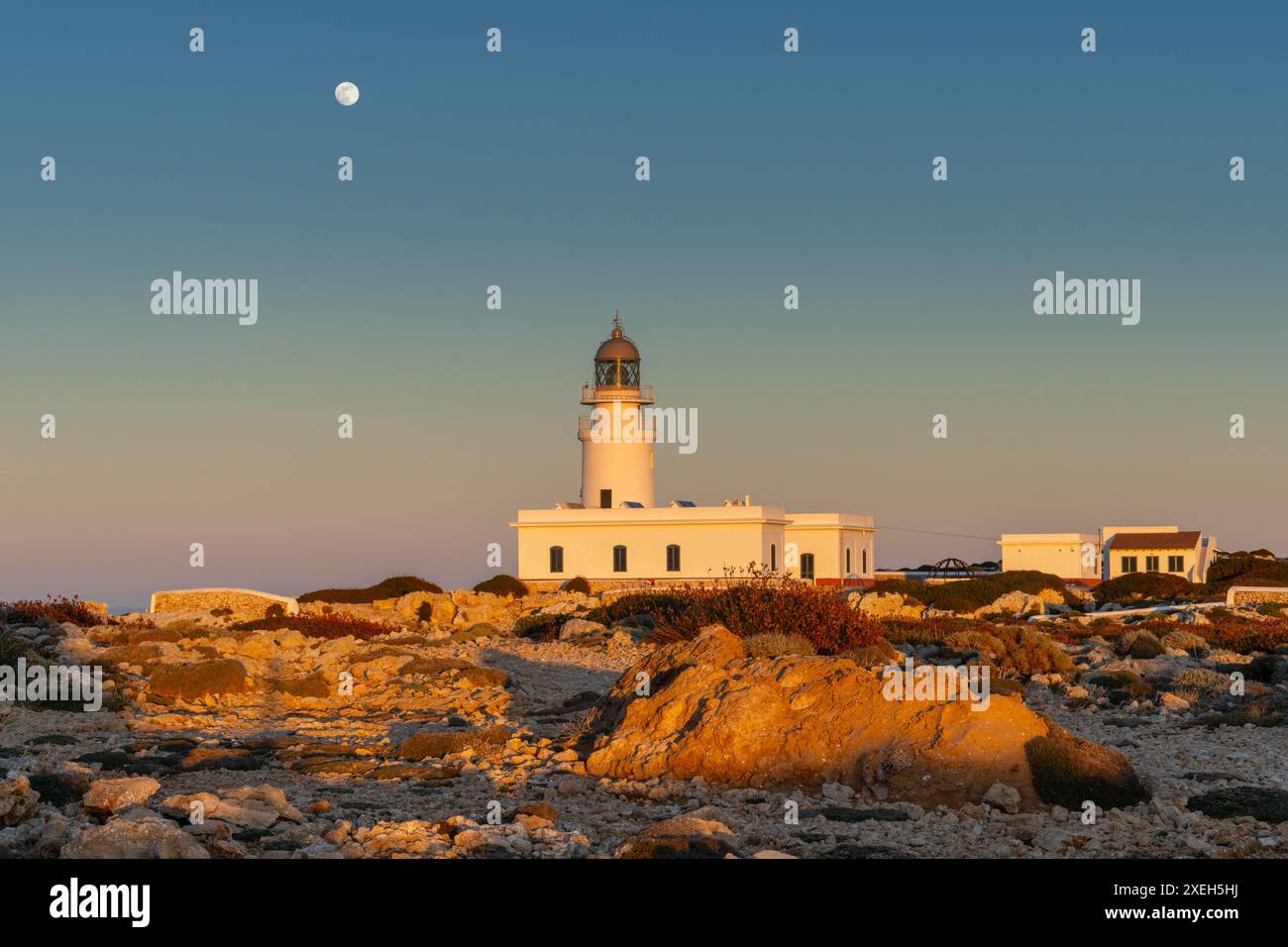 Blick auf den Leuchtturm Cap de Cavalleria auf Menorca bei Sonnenuntergang bei Vollmond Stockfoto