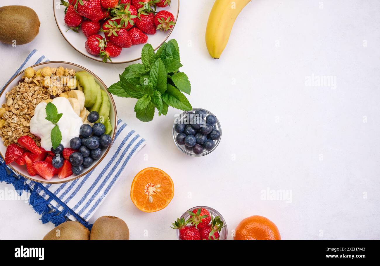Müsli mit Erdbeeren, Kiwi, Banane und Heidelbeeren in einem runden Teller auf einem weißen Tisch. Gesundes und leckeres Essen, Blick von oben Stockfoto