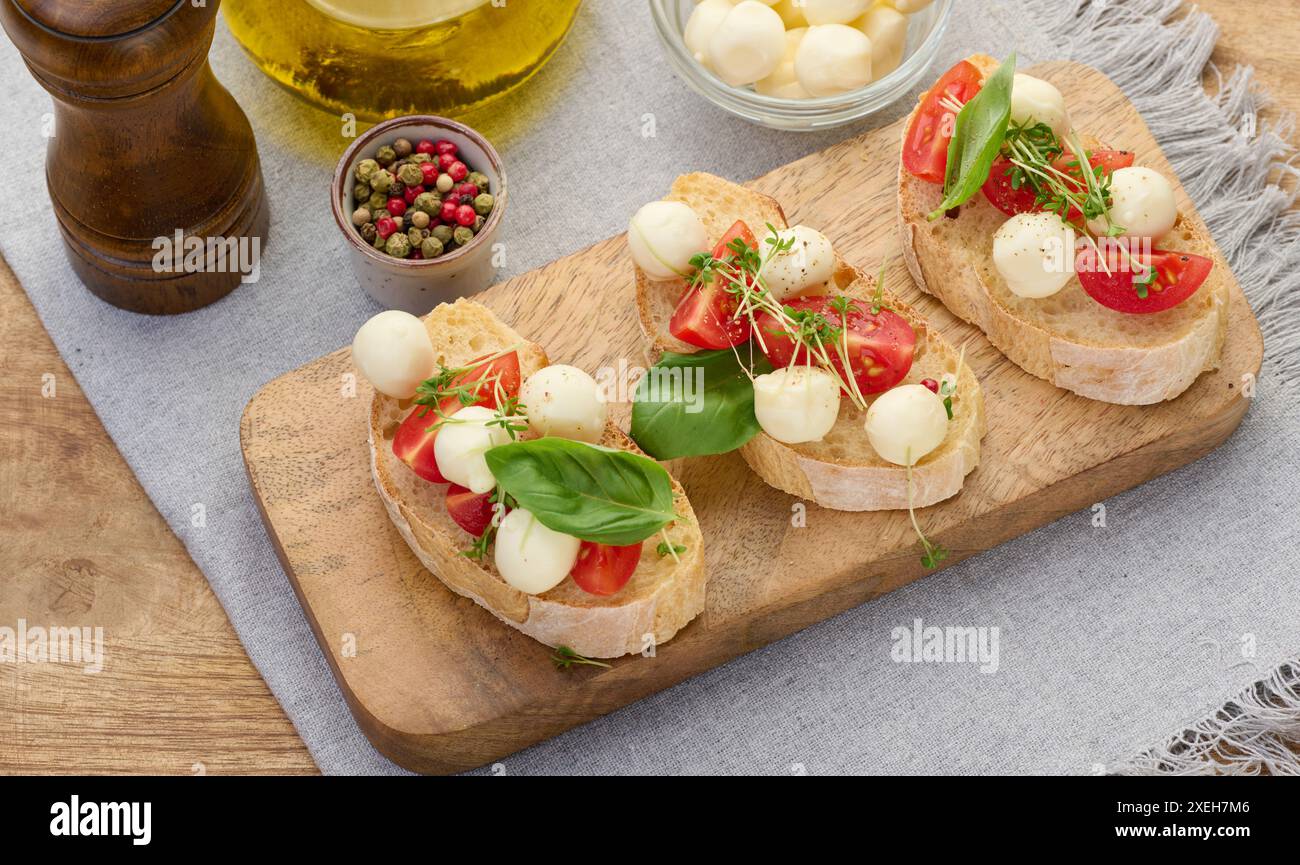 Runder Mozzarella, Kirschtomaten und Mikrogrün auf einem Stück Weißbrot, ein gesundes Sandwich Stockfoto