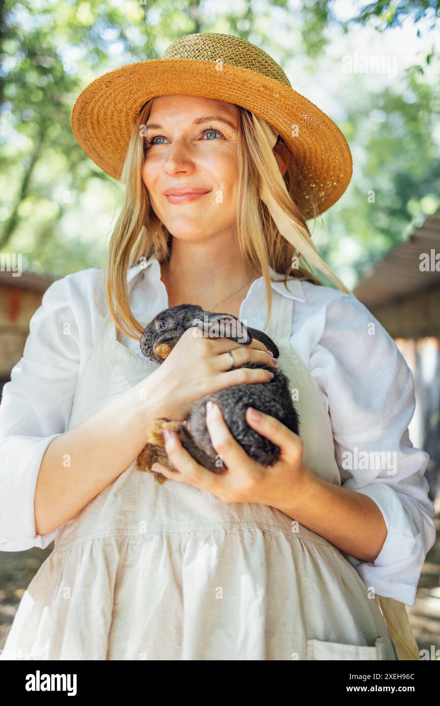 Nahaufnahme einer jungen, schönen Frau, die ein kleines schwarzes Kaninchen hält Stockfoto