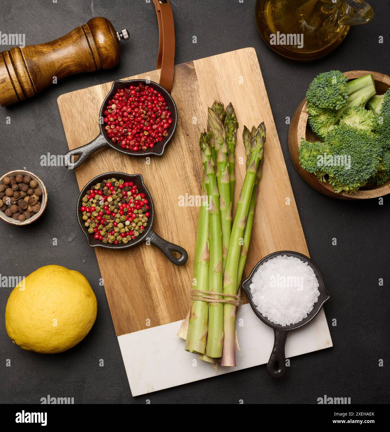 Roher Spargel, Brokkoli und Gewürze auf schwarzem Hintergrund Stockfoto
