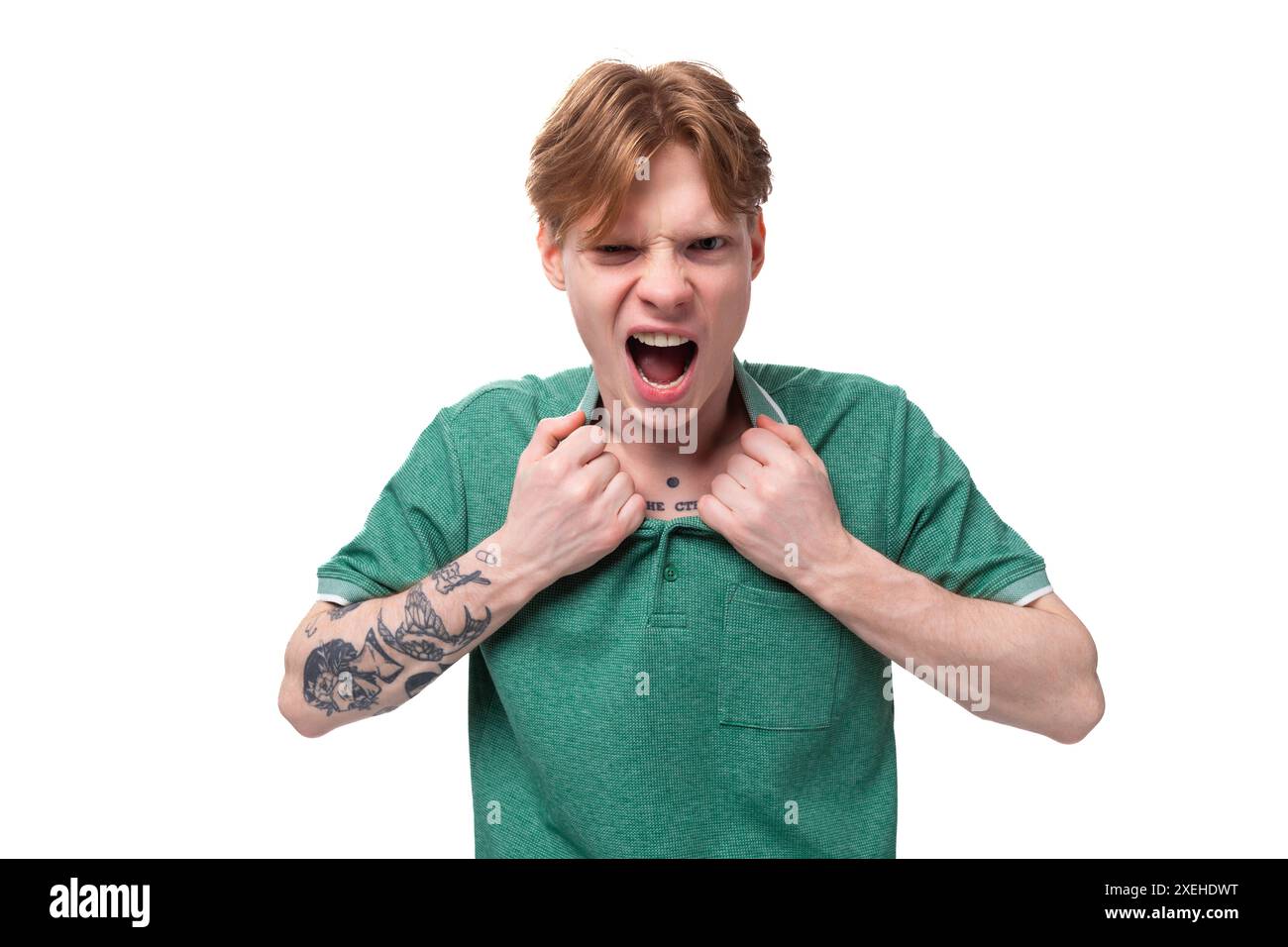 Ein junger, heller Ginger-Mann mit einem Tattoo am Arm, in einem grünen Kurzarm-T-Shirt gekleidet, schreit vor Wut Stockfoto