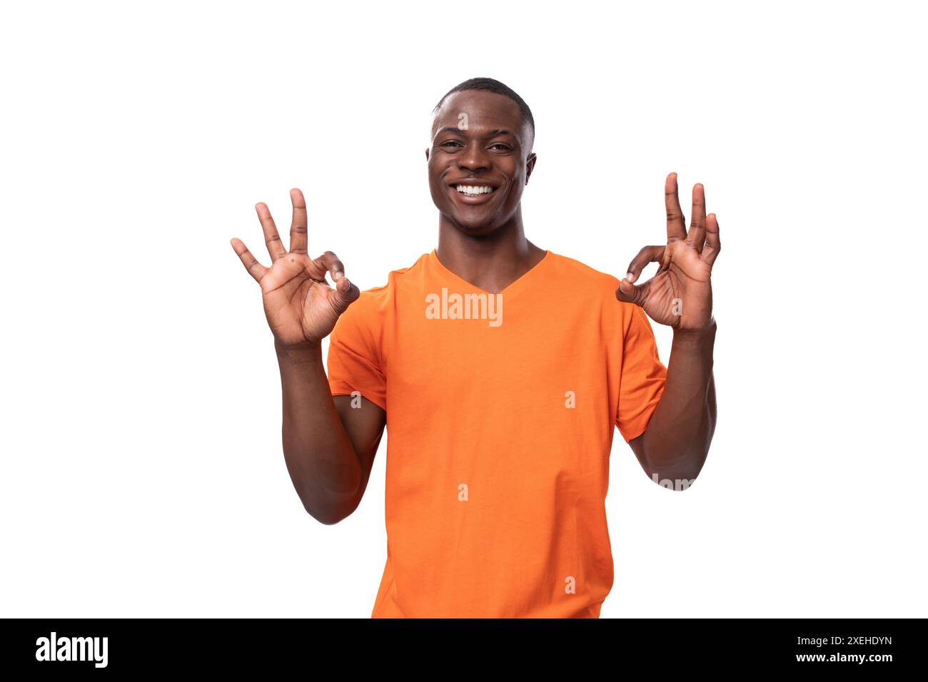 Junger afrikaner in einem orangen T-Shirt zeigt gute Geste und Lächeln Stockfoto