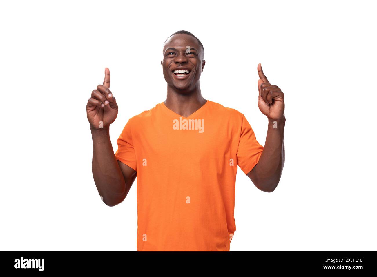 Junger amerikanischer Mann in einem orangen T-Shirt mit einem Mockup, der mit dem Finger auf die Nachrichten zeigt Stockfoto