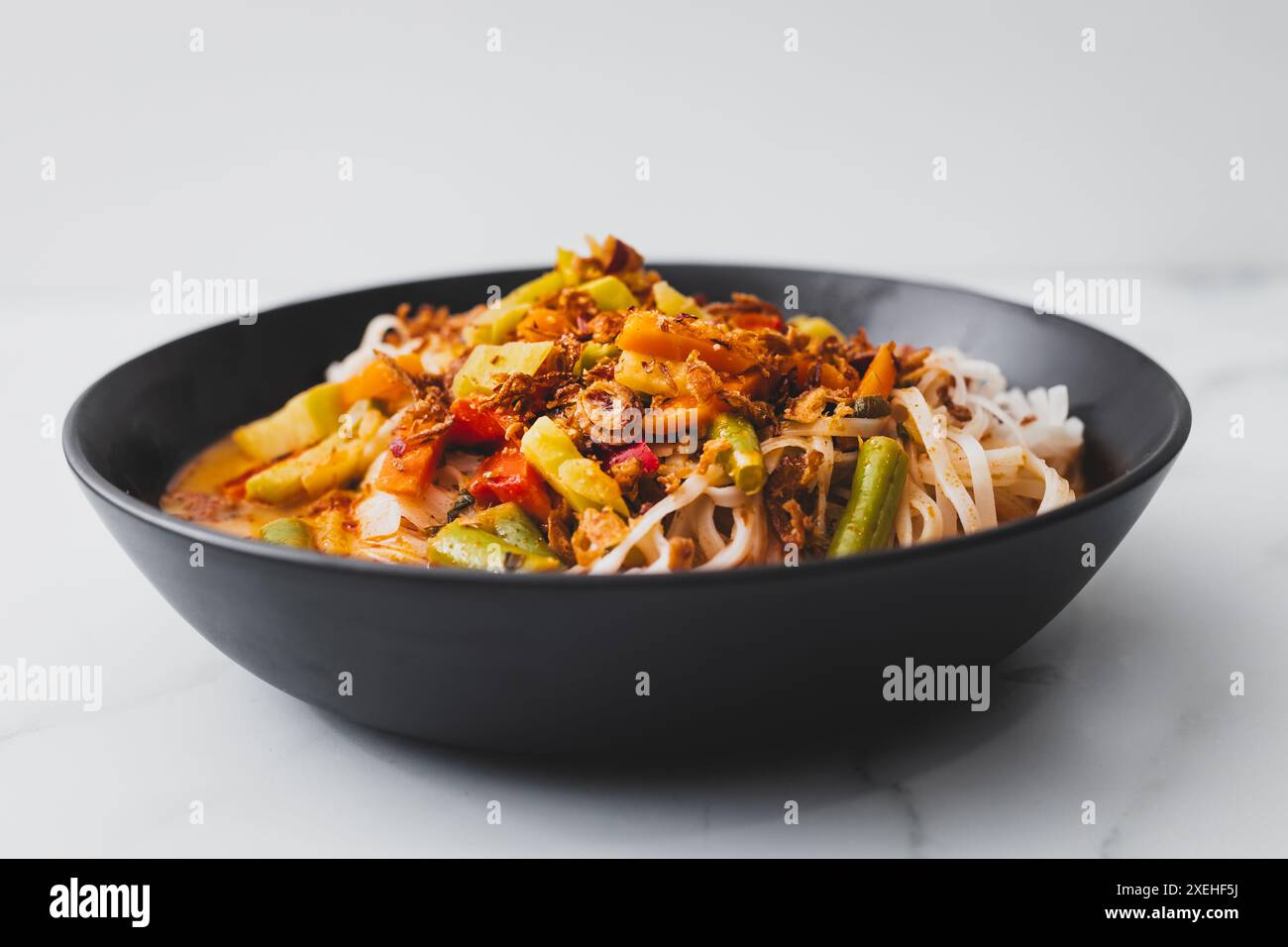 Pflanzliche Dan Dan Dan Reisnudeln Suppe mit gemischtem Gemüse und scharfer Sauce, gesunde vegane Lebensmittelrezepte Stockfoto