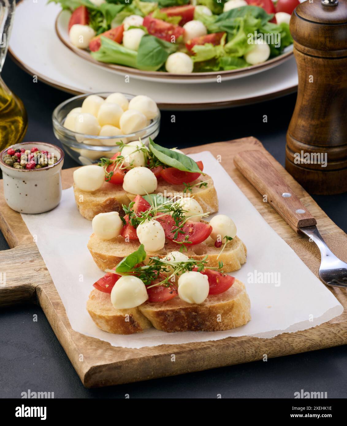 Runder Mozzarella, Kirschtomaten und Mikrogrün auf einem Stück Weißbrot Stockfoto