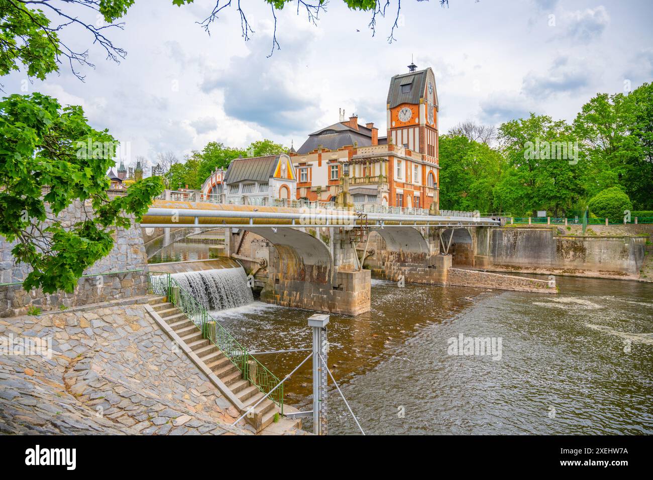 Das Jugendstilgebäude des Wasserkraftwerks Hucak in Hradec Kralove, Tschechien, ist mit einer Brücke über einen fließenden Fluss abgebildet. Stockfoto