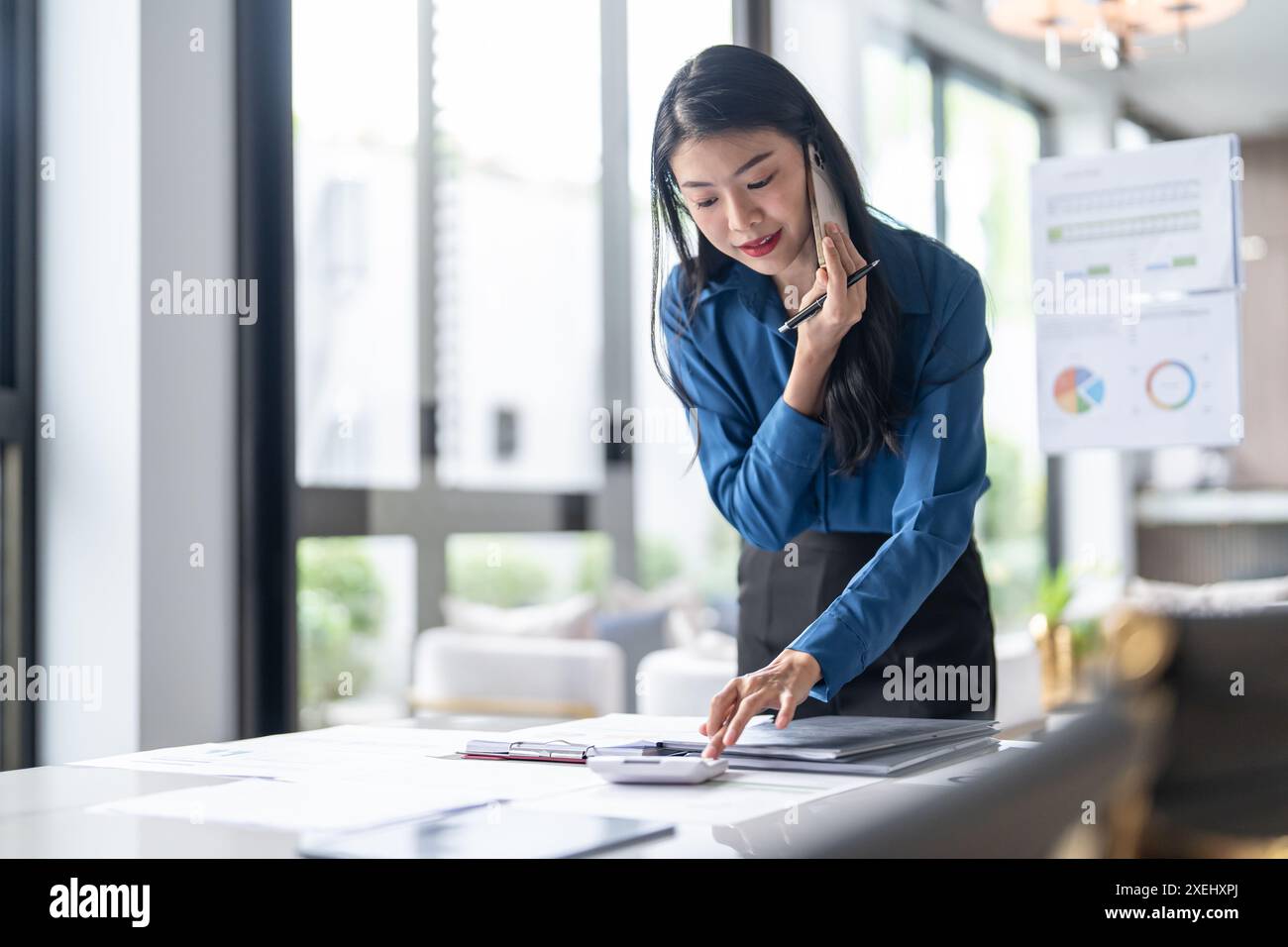 BeautifulÂ selbstbewusste asiatische Sekretärin clevere, professionelle Geschäftsfrau im Gespräch über phoneÂ Â in Â officeà¹ƒ Stockfoto