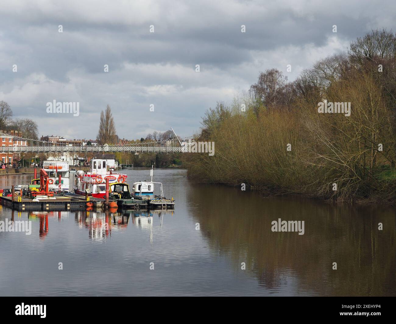 Blick auf den Fluss Dee in Chester mit Ausflugsbooten am Ufer und der Hängebrücke des Queens Park Stockfoto