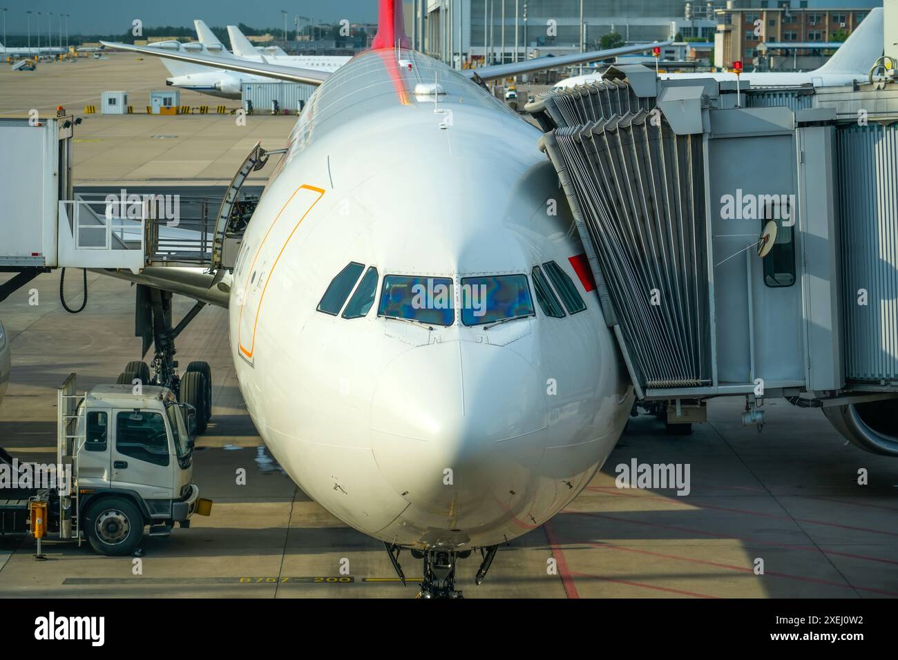 Blick direkt in das Cockpit: Weiße, breite Passagierflugzeuge stehen an der Bordbrücke auf dem Flughafenvorfeld. Stockfoto