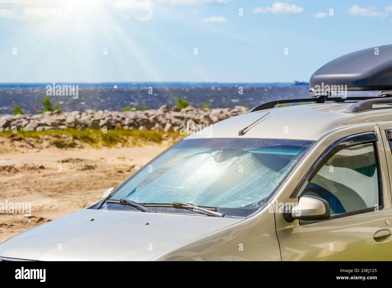 Schützende reflektierende Oberfläche unter der Windschutzscheibe der Passagiernarbe, die an einem heißen Tag geparkt ist und von den Sonnenstrahlen im Inneren am Strand des Meeres beheizt wird Stockfoto
