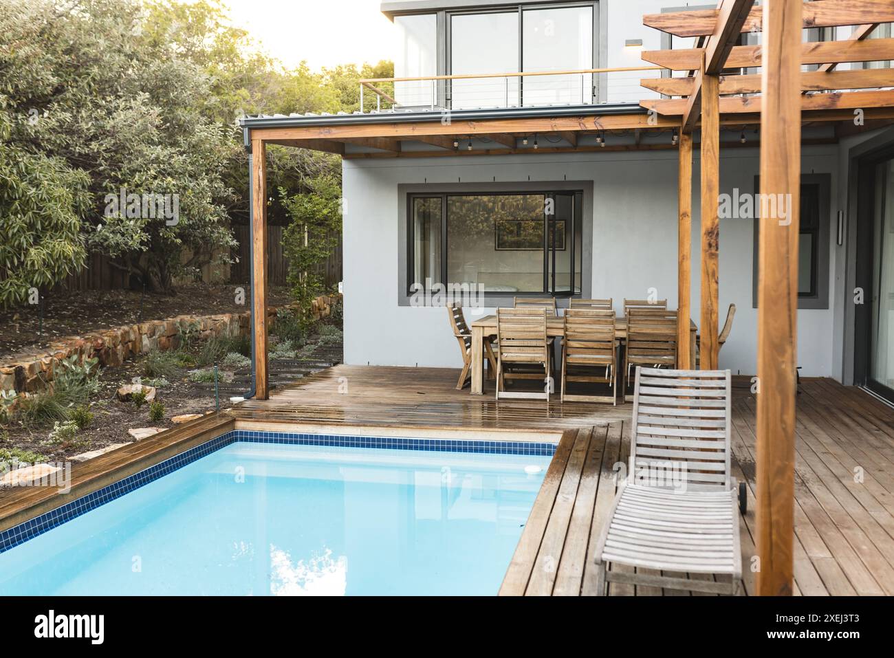 Terrasse im Freien mit Holzmöbeln und Swimmingpool, moderne Wohnanlage, Kopierraum Stockfoto