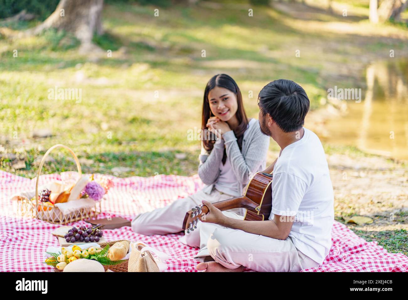 Verliebtes Paar genießt Picknickzeit beim Gitarrenspielen im Park Picknick im Freien. Glückliches Paar, das togetherÂ mit Picknickkorb entspannt Stockfoto