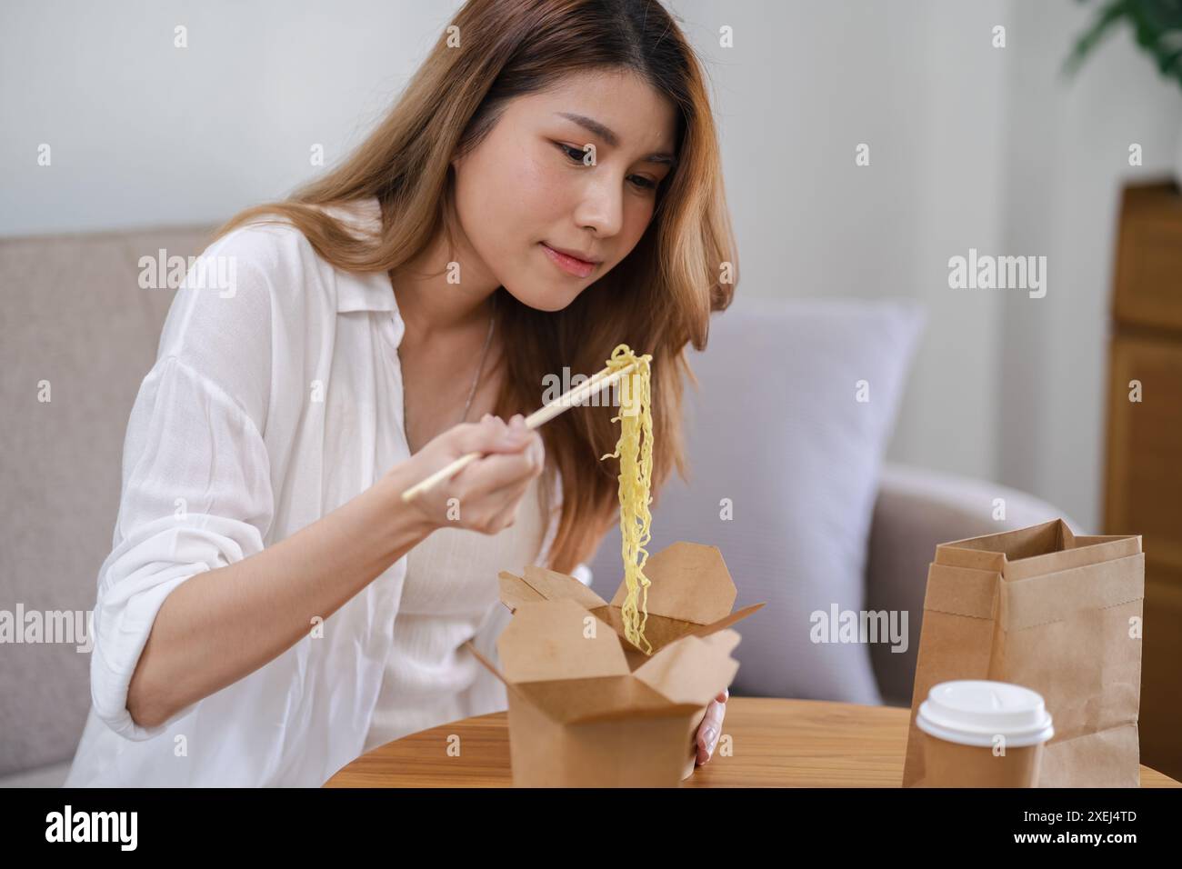 Asiatische Frau mit Essen und Getränken zum Mitnehmen zu Hause. Verzehr eatingÂ Lebensmittel nach Hause. Genießen Sie köstliche Lieferung zum Mitnehmen Stockfoto