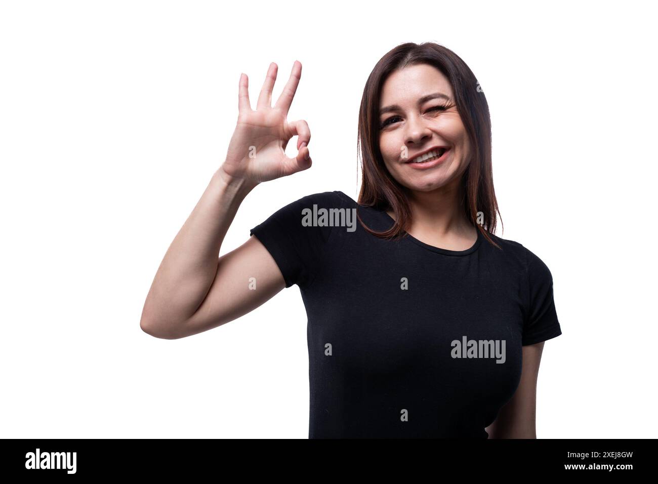 Positive, hübsche junge Brünette, die ein schwarzes T-Shirt auf weißem Hintergrund mit Kopierraum trägt Stockfoto