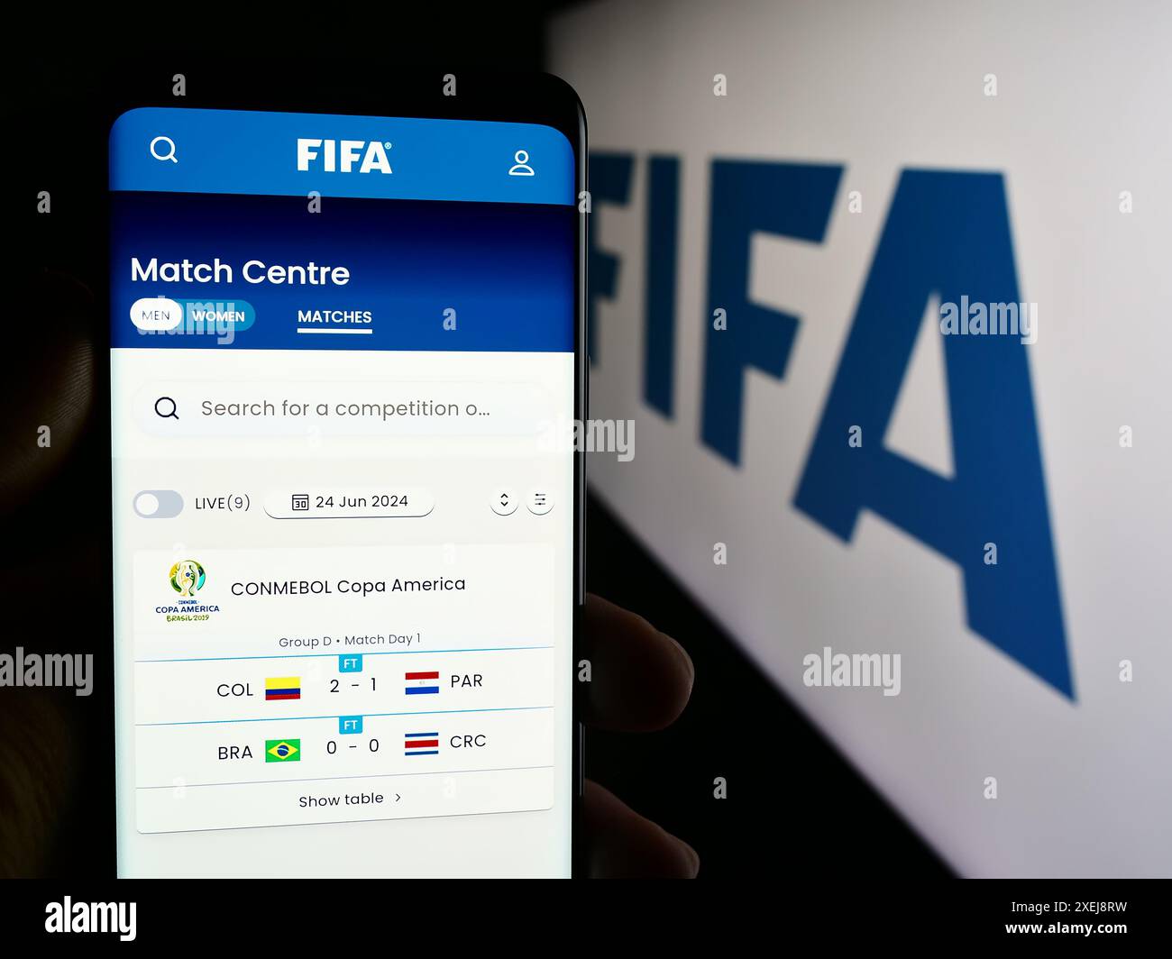 Person, die ein Mobiltelefon hält, mit Webseite des Fußballverbandes Internationale de Football Association (FIFA) mit Logo. Konzentrieren Sie sich auf die Mitte des Telefondisplays. Stockfoto