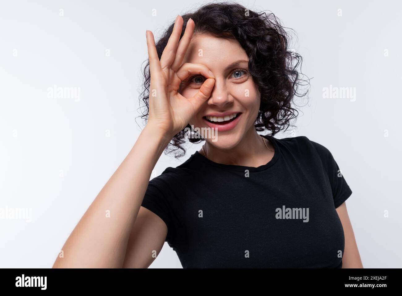 Porträt einer hübschen Frau mit Dauerwelle, die ein einfaches T-Shirt trägt Stockfoto
