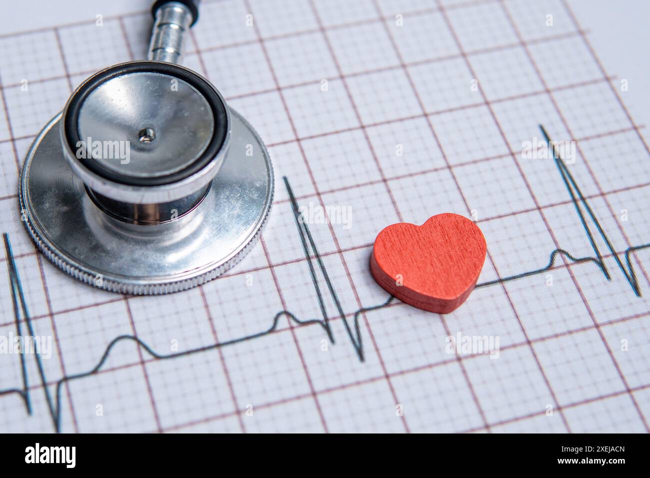 Nahaufnahme eines Stethoskops und eines roten Herzens auf einem Elektrokardiogramm (EKG)-Ausdruck. Das EKG-Diagramm zeigt einen normalen Sinusrhythmus. Stockfoto