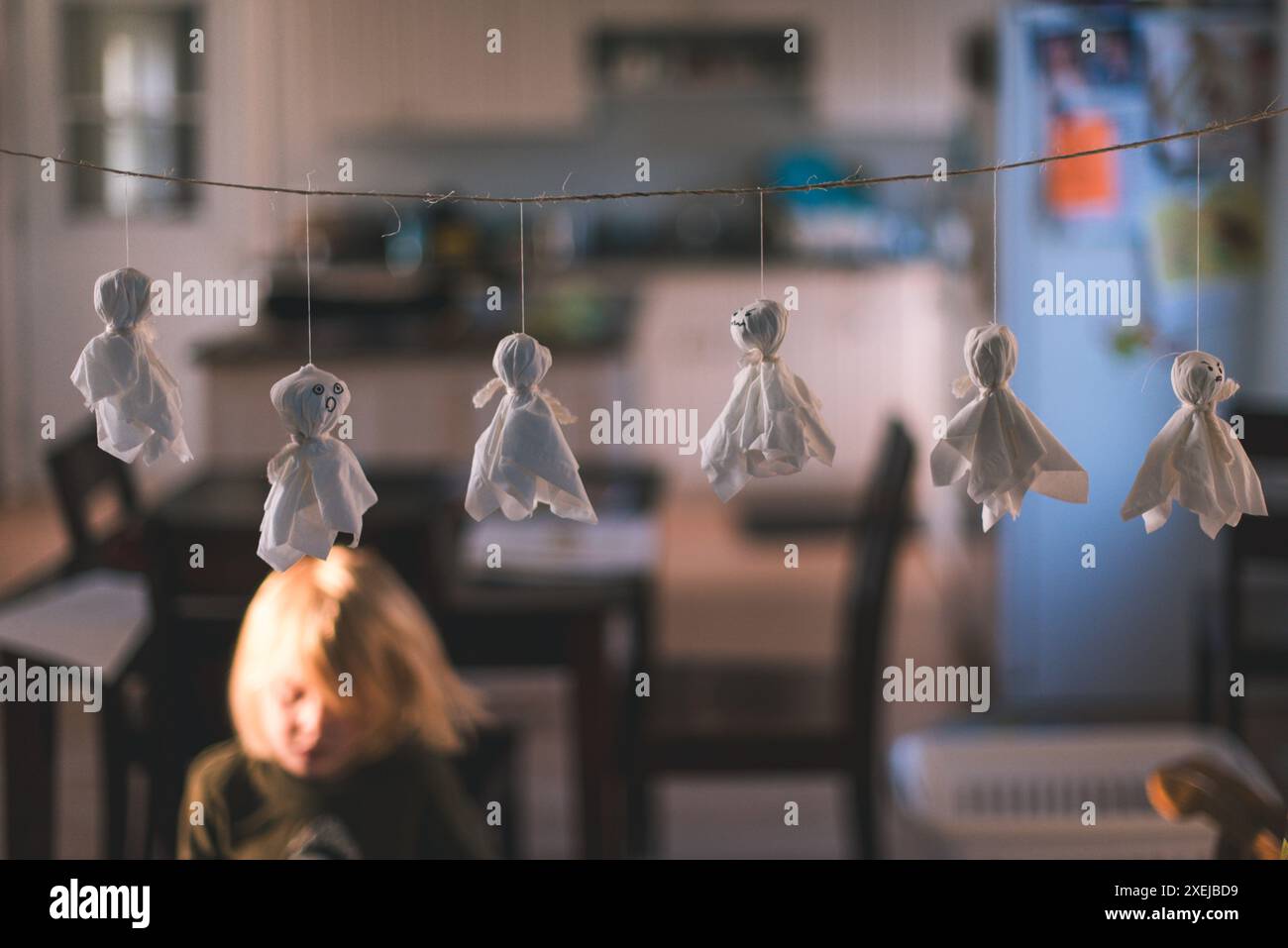 Kleine Geisterdekorationen hängen drinnen mit einem Kind an einer Schnur Stockfoto