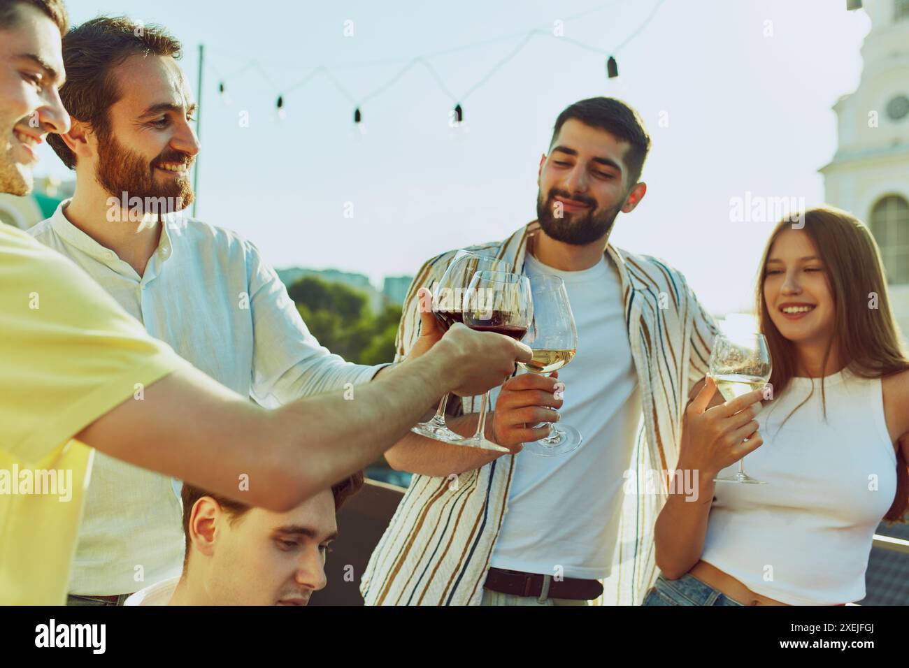 Freunde, die ihre Gläser in lebhaftem Toast anstoßen, genießen den sonnigen Tag und die Gesellschaft des anderen. Alkoholische Cocktails. Stockfoto